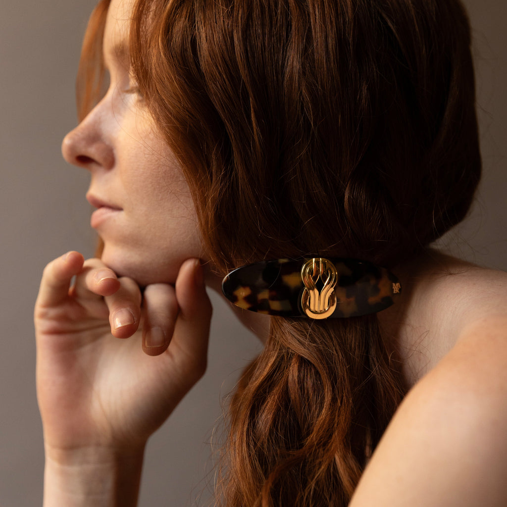 Coiffure chic avec une barrette à cheveux de luxe en acétate et laiton doré fabriquée en France par des artisans de couleur écaille de tortue, ligne Knot Or Mauliébris 